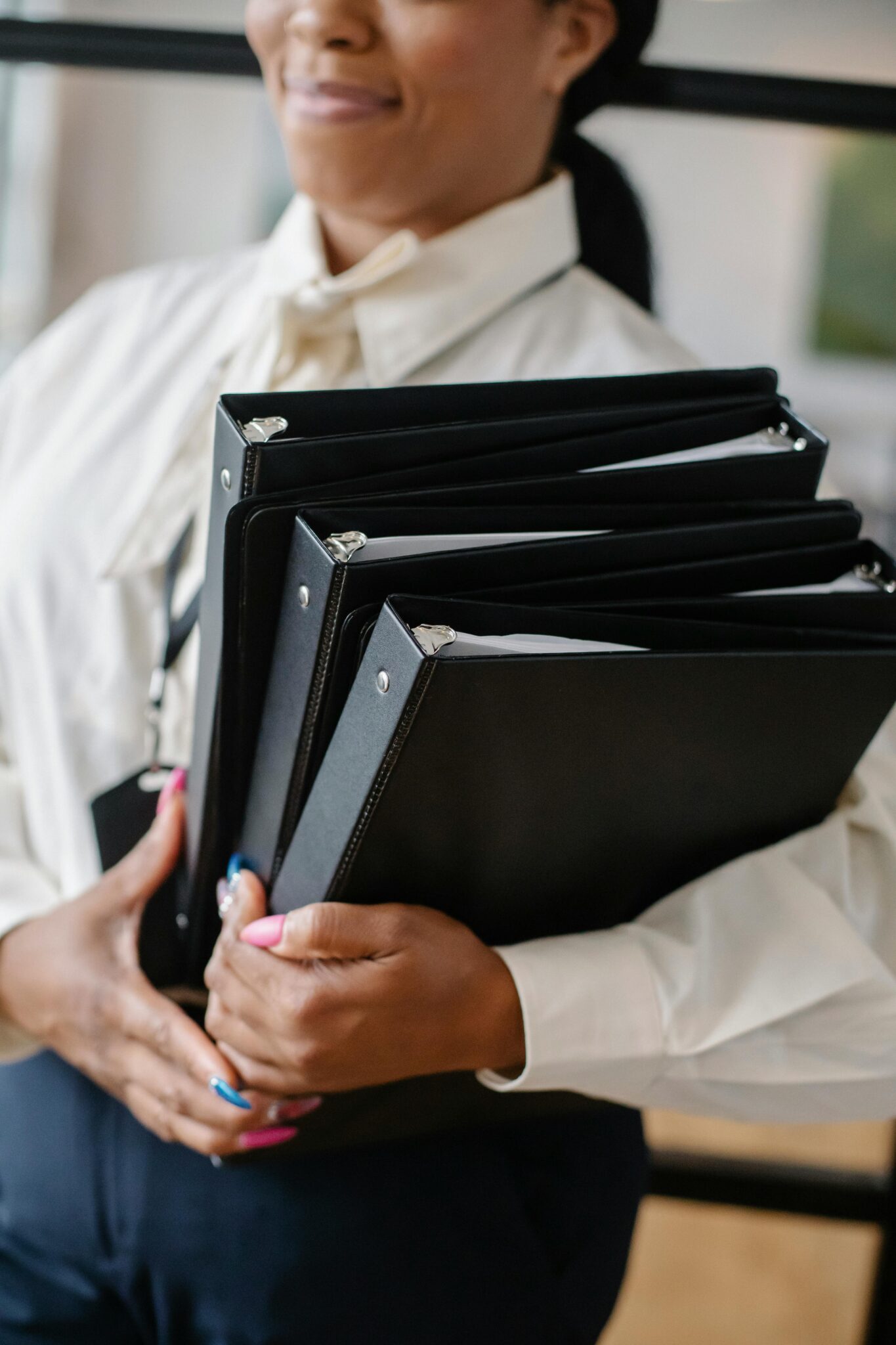Crop African American businesswoman with folders of documents and files standing in office room